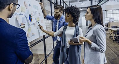 Professionals brainstorming in front of a whiteboard with charts and graphs.
